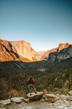 a woman standing on top of a rock in the mountains