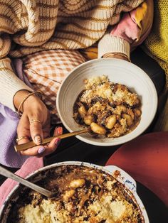 two people holding bowls of food on top of a table