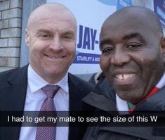 two men standing next to each other in front of a building