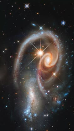 two spiral shaped objects in the middle of a space filled with stars and bright lights