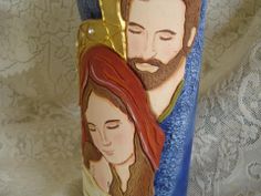 a ceramic vase with the image of jesus and mary on it's side, sitting on a lace covered surface