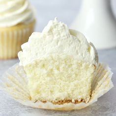 a cupcake with white frosting sitting on top of a table