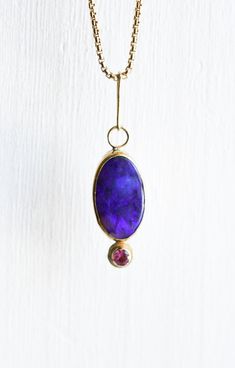 This stunning Lightning Ridge Black Opal is set in an 18k yellow gold bezel on a sterling silver backplate. The opal measures 22 mm by 12 mm. It is accented with a 4 mm Pink Tourmaline set in 18k yellow gold. Chain not included. Elegant Pink Opal Yellow Gold Jewelry, Gold Oval Pink Opal Jewelry, Oval Pink Opal Gold Jewelry, Oval Gold Jewelry With Pink Opal, Lightning Ridge Black Opal, 18k Gold Jewelry, Lightning Ridge, Yellow Gold Chain, Australian Opal