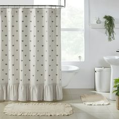 a bath room with a toilet and a shower curtain next to a tub in front of a window