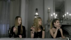 three beautiful young women sitting at a table with wine glasses in front of their faces