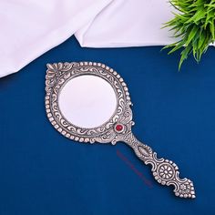 a mirror sitting on top of a blue table next to a white pillow and green plant