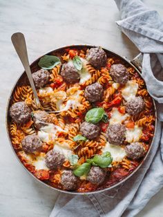 a pan filled with meatballs and pasta on top of a table