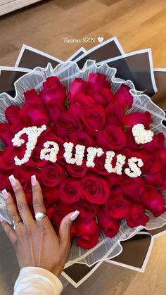 someone is holding a bouquet of roses with the word taurus spelled in white letters