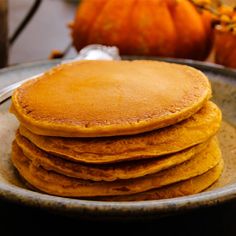 a stack of pancakes sitting on top of a plate next to a knife and fork