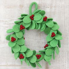 a green felt wreath with red berries on it