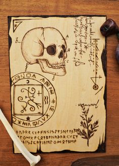 a wooden plaque with a skull and some writing on it next to an ink pen