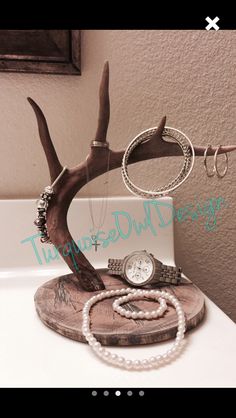 a deer's antler with rings and bracelets on top of it next to a white sink