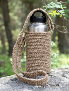 a crocheted water bottle holder on top of a rock