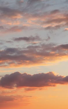 a plane flying in the sky at sunset with clouds and sun going down behind it