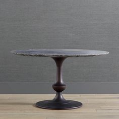 a small round table on a wooden floor in front of a gray wall and wood floors