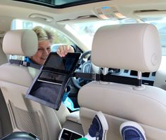 a woman sitting in the back seat of a car holding an electronic device