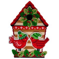 a bird house with two red birds on it's roof and holly wreaths