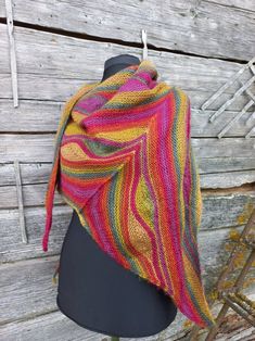 a multicolored knitted shawl draped on a mannequin headdress