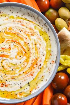 a white bowl filled with dip surrounded by assorted vegetables