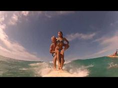 two people riding surfboards on top of a wave in the ocean while another person swims behind them