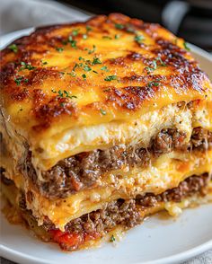 a close up of a plate of food with lasagna on the bottom and cheese