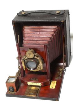 an old fashioned camera sitting on top of a wooden stand