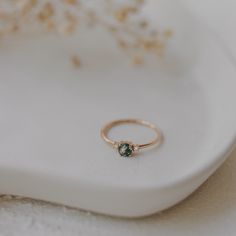 a gold ring with a green stone sits on a white plate