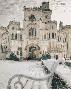 a snow covered bench in front of a castle