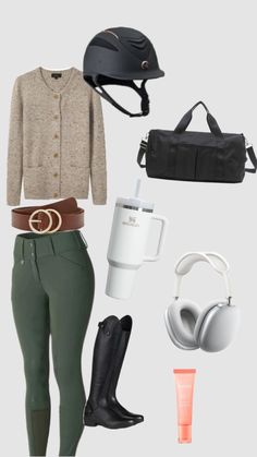 a woman wearing green pants and black boots is standing next to her purse, hat, jacket, booties, headphones, and handbag