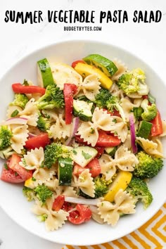 a white bowl filled with pasta salad on top of a yellow and white table cloth