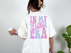 In my Teacher Era Shirt! In my Teacher Era Sweatshirt! 📍Handmade with Love! 📍Shirts are Unisex TShirts and SO Soft!! We proudly use Bella Canvas! 📍These are True to Size, Size Charts are provided on each listing. 📍Colors Available will be listed on each listing. 📍DESIGN is Sublimation.  📍Processing Time: 3-5 business days. Shipping Options available at check out. 📍Returns & Exchanges: No returns or exchanges will be accepted as these are made to order. If you have an issue with your item Retro Relaxed Fit Tops For School, Trendy School Tops With Funny Text, Retro White Tops For Back To School, Retro School Tops With Slogan, Retro White School Shirt, Relaxed Fit Shirt For School With School Spirit, Retro White Shirt For School, Cute Relaxed Fit Shirt For School, Relaxed Fit Shirt With School Spirit