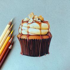 a drawing of a cupcake with icing and nuts on it next to colored pencils