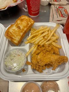 chicken, french fries and coleslaw are on a plastic tray with dipping sauces