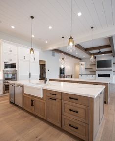 a large kitchen with an island in the middle and two pendant lights hanging from the ceiling