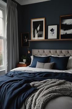 a bedroom with dark blue walls, white bedding and pictures on the wall above it