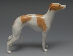 a brown and white dog figurine on a gray background with an orange spot