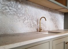 a kitchen counter with a gold faucet next to a sink and cupboards