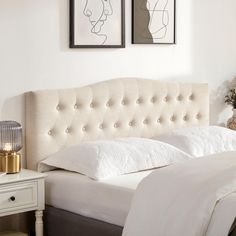 a white bed with two pictures above it