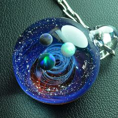 a glass pendant with planets in it on a leather surface