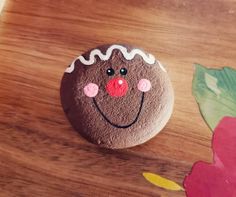 a close up of a rock with a face painted on it and flowers in the background