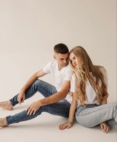 a man and woman are sitting on the floor posing for a photo with their arms around each other