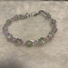 a close up of a bracelet on a white surface with beads and silver clasps