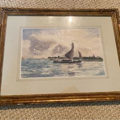 a painting hanging on the wall next to a framed object with a sailboat in it