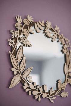 a mirror that is on the wall with leaves and flowers cut out of it's sides