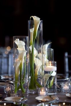 an image of a table setting with flowers in vases and candles on the table