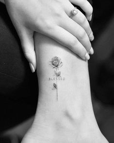 a woman's foot with a small tattoo on it that reads, blessed and a rose