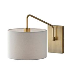 a wall mounted light with a white shade on the side and a gold metal arm