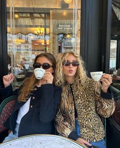 two women sitting at a table drinking coffee