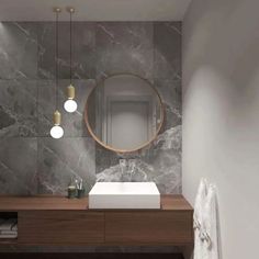 a modern bathroom with marble walls and flooring, along with a round mirror above the sink