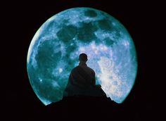 a man sitting on top of a roof in front of a large blue full moon